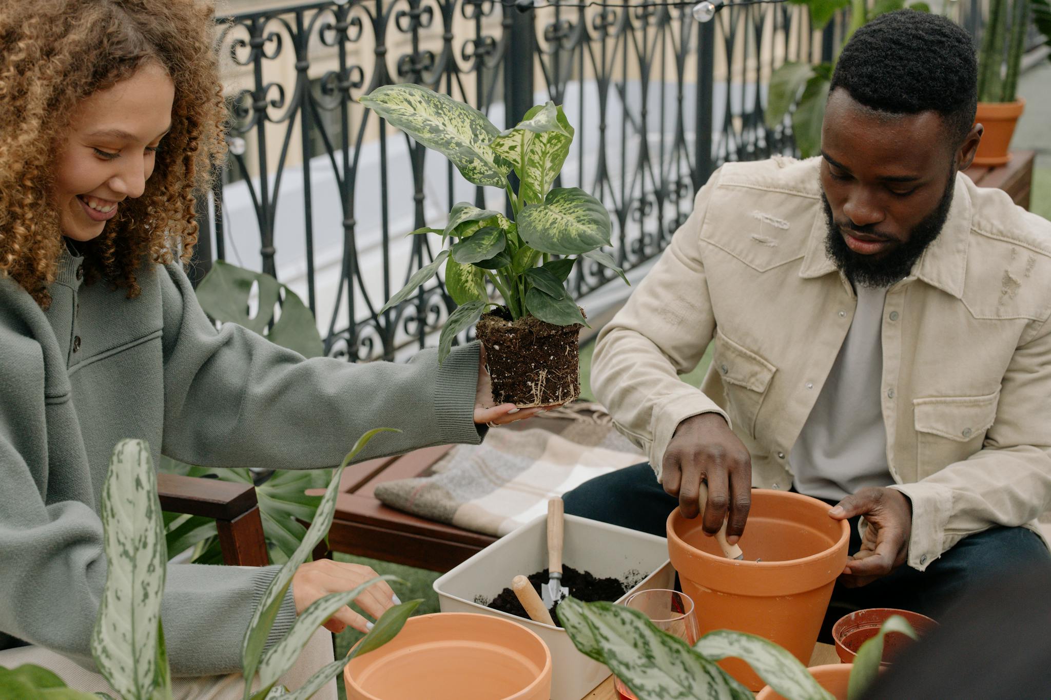 Two friends potting plants together indoors, enjoying a relaxed gardening session on a balcony.